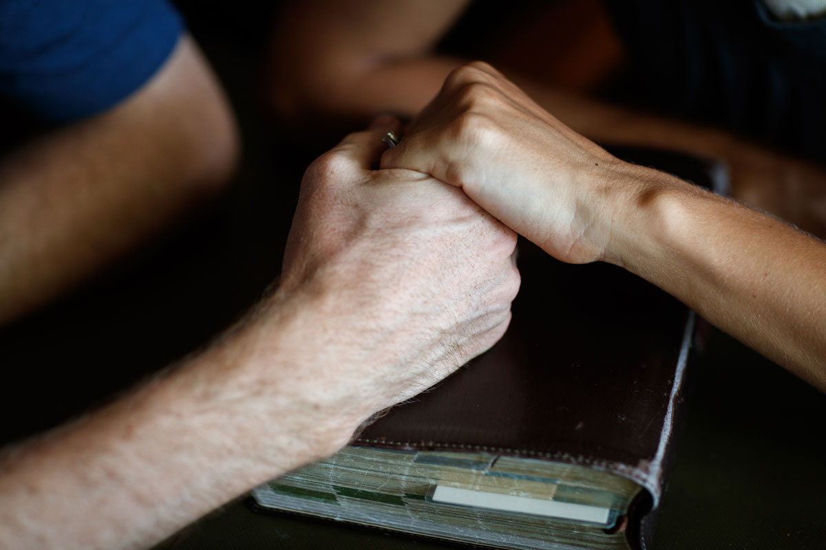 Holding hands over a Bible.